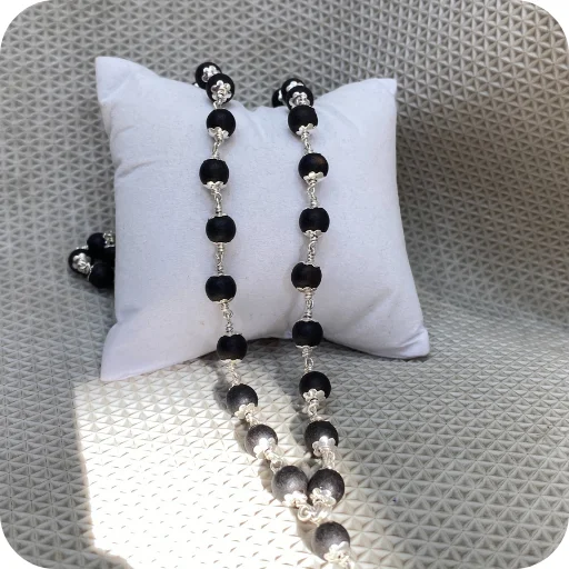 silver-plated-karungali-mala-white-cushion.webp silver plated Karungali mala on white cushion spiritual beads necklace