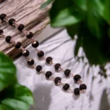 silver plated Karungali mala with half wood natural scenery background